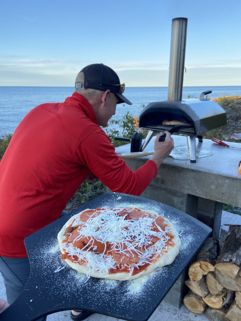 Jason Makela, co-owner of Fresh Coast Cabins, firing up pizza for guests in their Ooni Karu wood-fired pizza oven on Lake Superior.